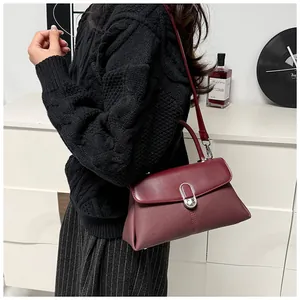 Vue latérale d'un sac à main texturé bordeaux porté avec un pull en maille noire