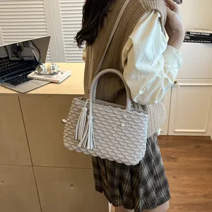 Light grey tote bag with fish scale pleats and tassel details in a lifestyle setting