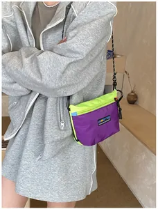 Detail der lila und neongrünen Outdoor-Umhängetasche aus Nylon mit grauem Trainingsanzug