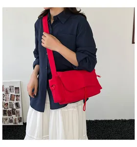 Dettaglio borsa a tracolla rossa con tracolla larga indossata da una modella blu