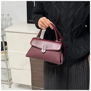 Détail d'un sac à main bordeaux en cuir avec fermoir rotatif argenté et côtés plissés