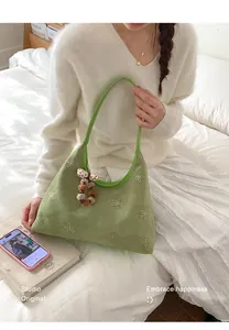 Dettaglio della borsa hobo verde con ricami floreali e ciondolo di perle morbide