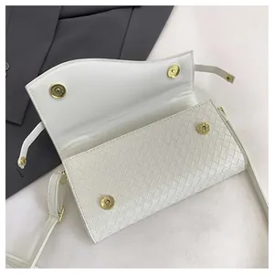 Detail of white woven flap bag showing golden magnetic buckles and textured finish