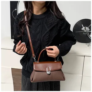 Détail d'un sac bandoulière marron bicolore avec fermoir rotatif argenté et poignée haute