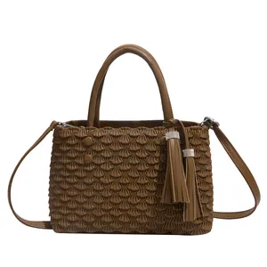 Brown pleated fish-scale tote bag with dual handles and long tassels on white background
