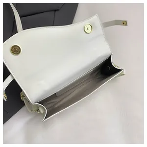 Detailed interior of a white woven texture handbag showing magnetic snaps and lining