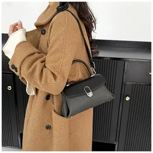 Détail d'un sac bandoulière en cuir noir avec fermoir métallique argenté porté par un mannequin