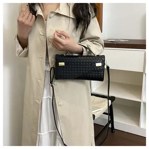 Detail of black woven leather handbag with gold buckles and integrated handle shown on model