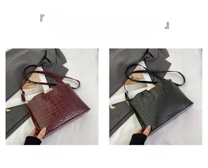 Detail of luxury crocodile pattern shoulder bags in burgundy and black with gold hardware