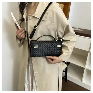 Detail of black woven leather handbag with gold metal accents and adjustable strap