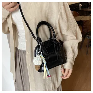 Close-up of black shell handbag with a knit ice cream charm and silver hardware