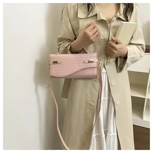 Detail of pink woven PU leather bag with gold hardware and adjustable strap on a model