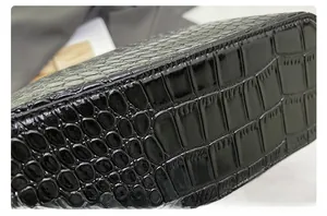 Detail view of glossy black crocodile embossed leather on handbag bottom and side seams