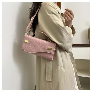 Pink woven leather handbag with gold buckles shown styled on a beige coat outfit