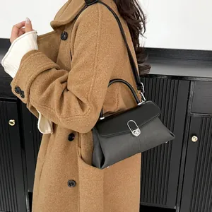Sac à main minimaliste en cuir noir avec fermoir argenté, porté par un mannequin