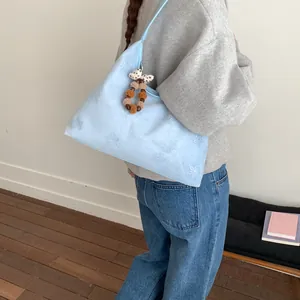Light blue faux suede shoulder bag with floral embroidery and bow pompom charm
