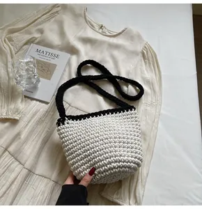 Close-up of handmade woven bucket bag showing black and white crochet texture and strap