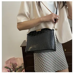 Detail of black crocodile texture shoulder bag with gold metal trim and buckle
