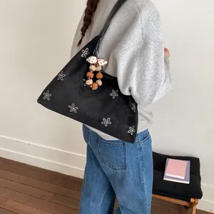 Chic black faux suede tote bag with rhinestone flower pattern and plush ball charm accessory