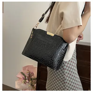 Detail of vintage black crocodile pattern shoulder bag with gold hardware and strap
