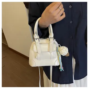 Detail of white shell-shaped handbag with glossy finish and cute ice cream charm