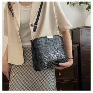 Detail of black crocodile texture leather shoulder bag with glossy finish and gold hardware