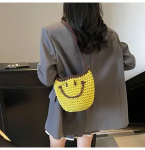 Detail of hand-woven yellow crochet bucket bag featuring a brown smiley face and braided strap