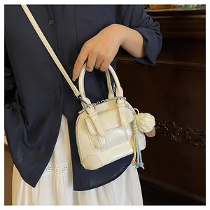 Detail of cream shell bag with top handle and cute crochet ice cream charm on strap