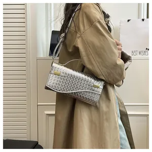 Silver woven crossbody bag with gold buckle detail shown on model with trench coat