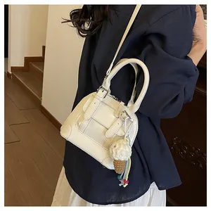 Detail of cream white shell bag with buckle straps and ice cream crochet charm accessory