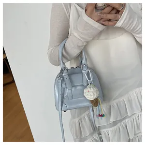 Light blue shell bag with plush ice cream charm shown on white ruffle dress