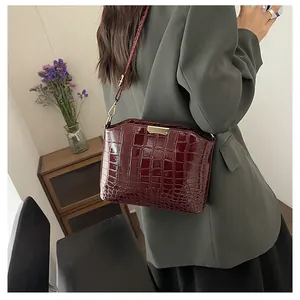 Detail of burgundy crocodile pattern shoulder bag with elegant gold metal buckle detail