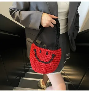 Detailed close-up of red and black hand-woven bucket bag with a smiling face design