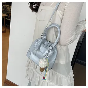 Light blue shell bag shown as crossbody with ice cream charm and silver hardware