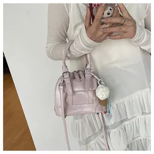 Detail of a pink shell-shaped handbag with a woven ice cream pendant and silver buckle