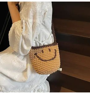 Close-up of hand-woven bucket bag with brown smile face pattern and shoulder strap