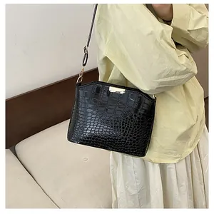 Detail of black crocodile texture bag with gold buckle on shoulder strap design