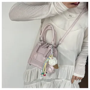 Detail of a pink patent leather shell bag with ice cream charm and silver hardware