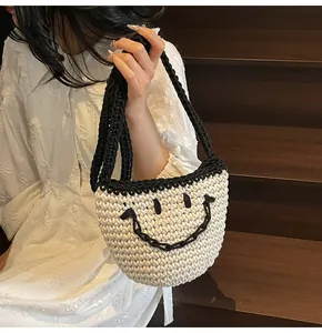 Detailed view of hand-woven cream bucket bag with black smile face and top handles