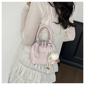 Detail view of pink leather shell bag worn with a white blouse and cute charm
