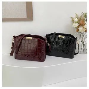 Detail of burgundy and black crocodile embossed crossbody bags with gold hardware