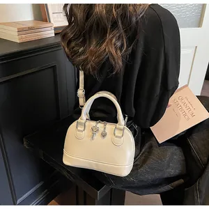 Détail du sac coquillage crème avec pendentif cœur, stylisé avec des livres et bois anciens