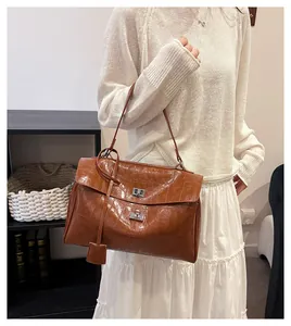 Detail of brown crocodile pattern handbag with silver metal twist lock and hanging pouch