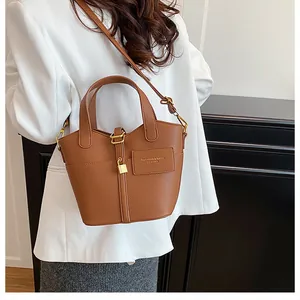 Détail du sac seau en cuir grainé marron avec cadenas doré et bandoulière