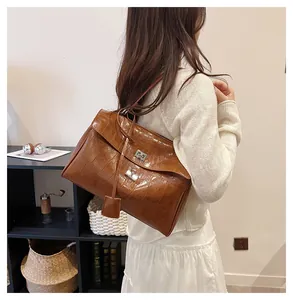 Detail shot of brown crocodile pattern leather handbag with silver metallic twist lock