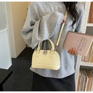 Photo lifestyle d'un sac à main beige en forme de coquille avec pendentif coeur