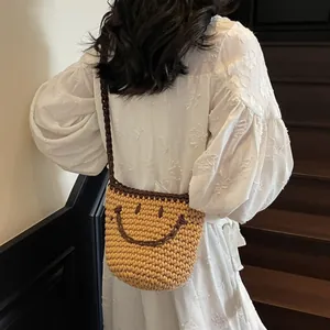 Handcrafted woven yellow bucket bag with a brown smile design and crossbody strap