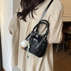 Chic black shell bag with glossy finish and knitted ice cream charm shown on model