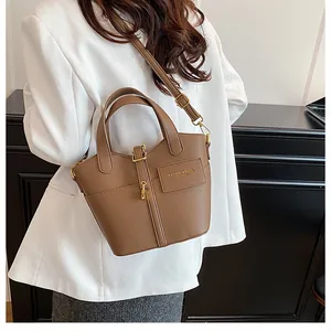 Détail du sac en cuir grainé marron avec logo doré et bandoulière amovible