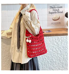Detail of red hollow knit tote bag featuring 3D white flowers and a green ribbon bow
